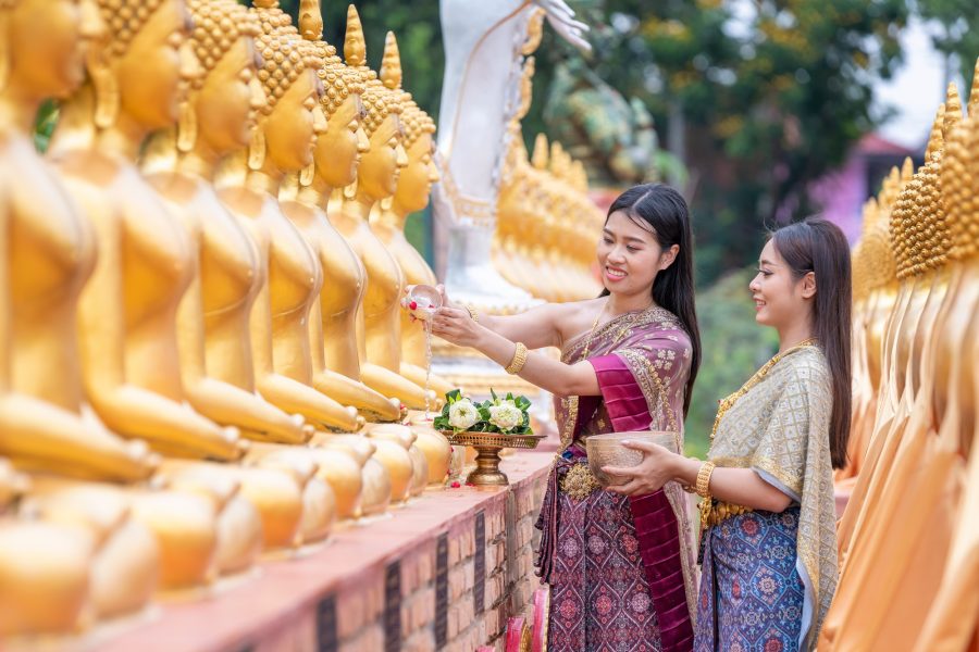 Asian woman wearing ancient Thai traditional dress holds garland and fresh flowers paying homage Bud